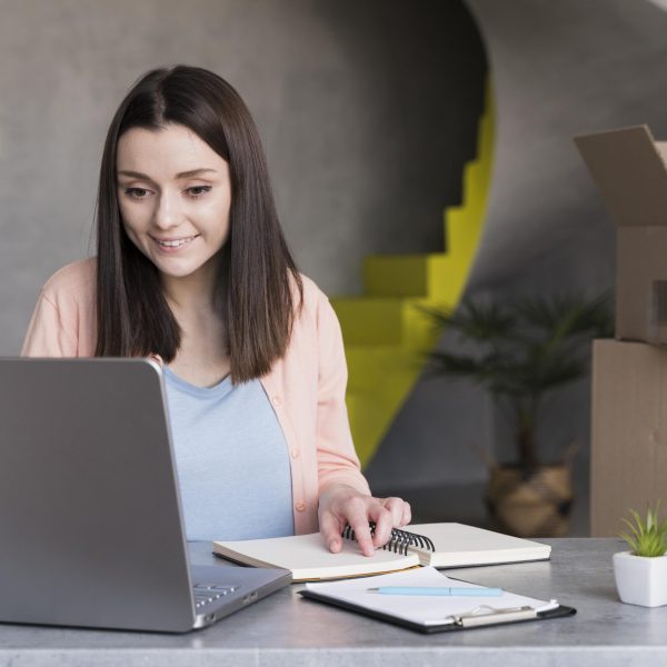 front-view-woman-working-laptop-with-boxes-back